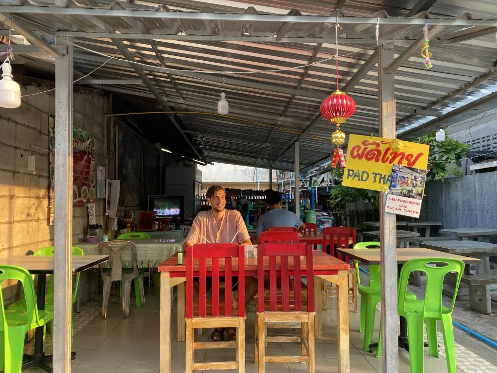 Front view picture of the local Thai restaurant with a man sitting at a table