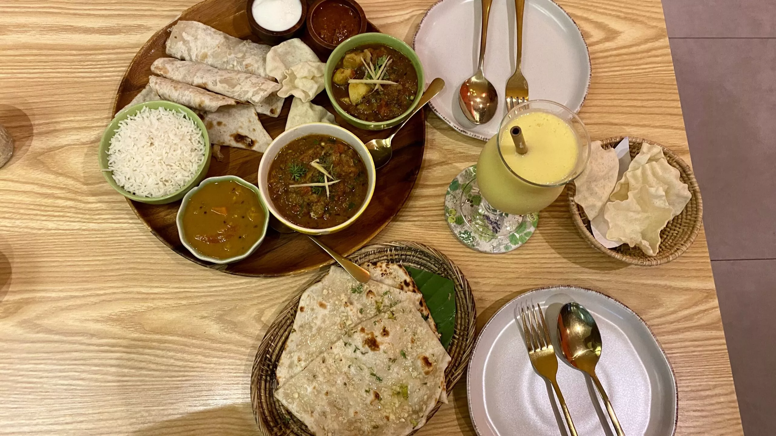 Up view on delicious Indian plate with roti, rice, mango lassy and and sauces